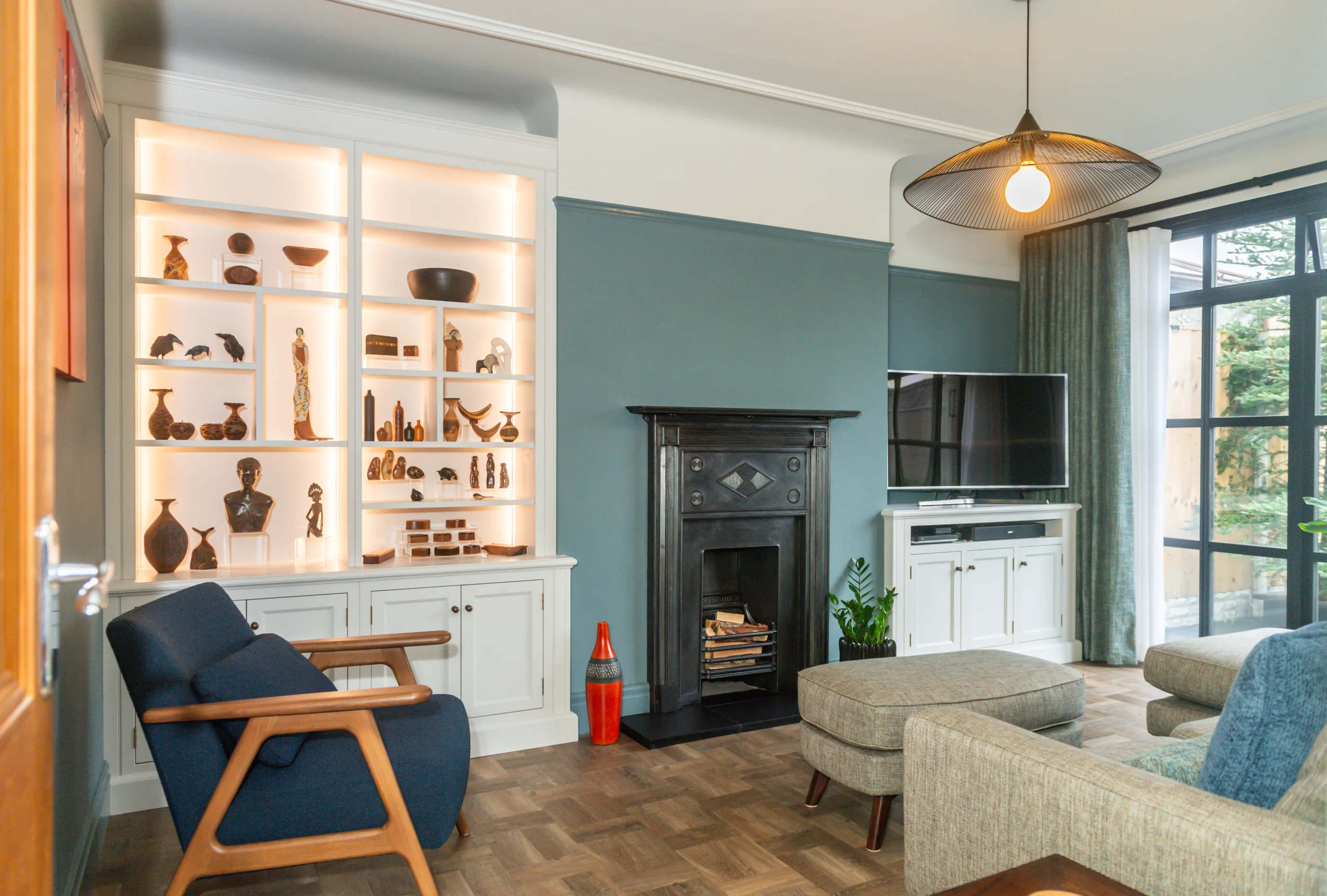 A sitting room with illuminated fitted display cabinetry beside a dark fireplace
