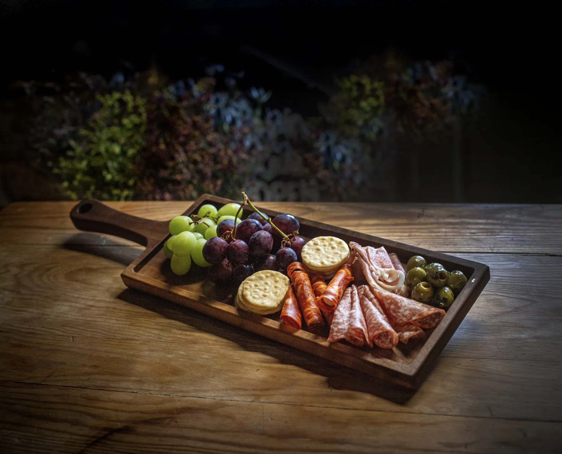 A Shakespeare and Taylor walnut charcuterie board laid with food for serving
